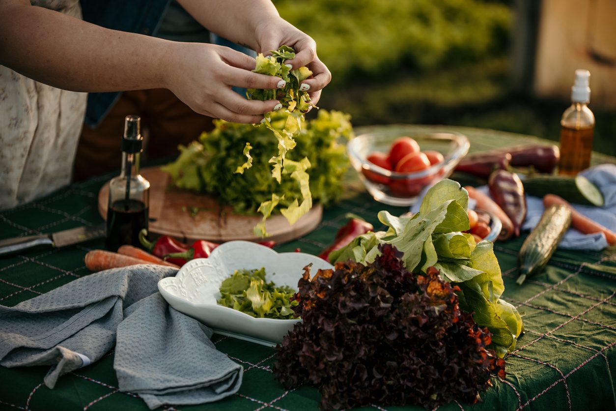 A person makes a salad from fresh produce obtain from farm-to-table delivery.